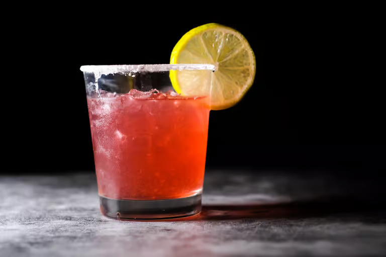 Red cocktail with citrus garnish at Moustache Lounge